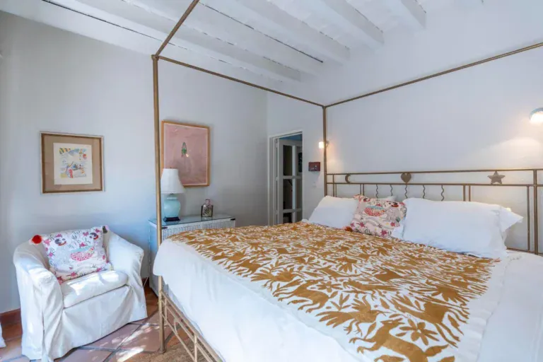 Casa Jardín, bedroom with a metal frame bed, an armchair and a beamed ceiling, San Miguel de Allende