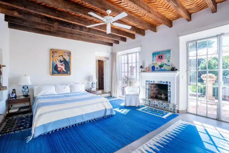 Casa Jardín, blue and white bedroom with a tiled fireplace and garden doors, San Miguel de Allende