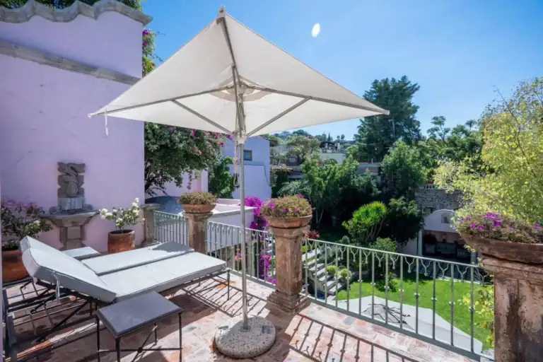Casa Jardín, upper terrace with a lounge chair and an umbrella over the garden, San Miguel de Allende