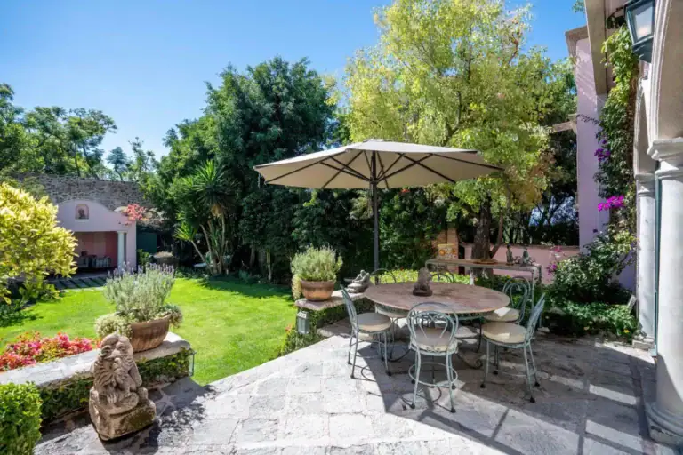 Casa Jardín, garden dining table under an umbrella on a stone patio, San Miguel de Allende