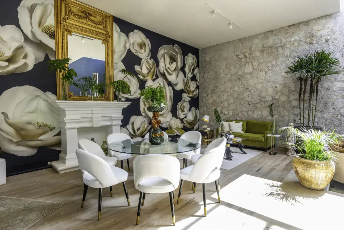 Casa Juan Guadiana, dining table with white chairs in front of a floral mural and a gold mirror, San Miguel de Allende