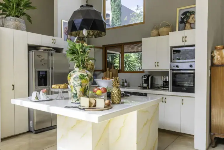 Casa Juan Guadiana, kitchen with white cabinets, a marble-look island and a black pendant, San Miguel de Allende