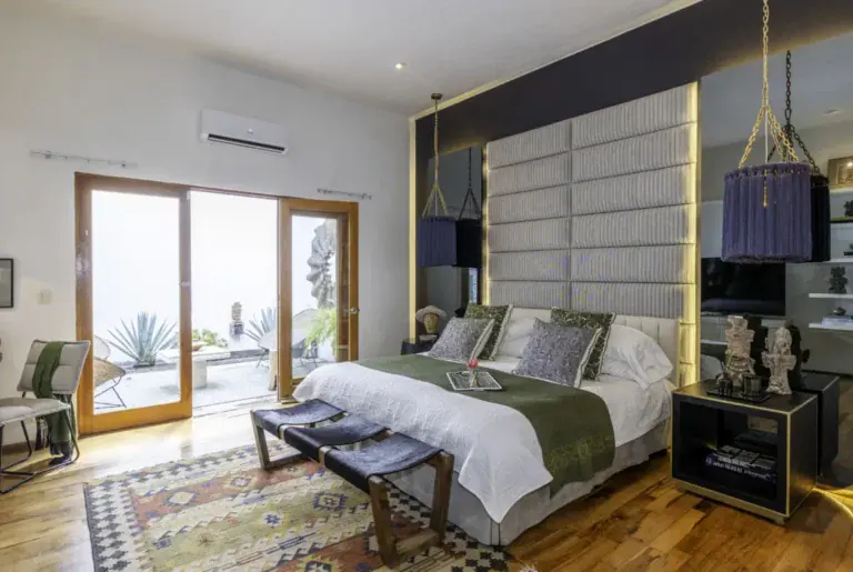 Casa Juan Guadiana, primary bedroom with a quilted gray headboard and sliding glass doors, San Miguel de Allende