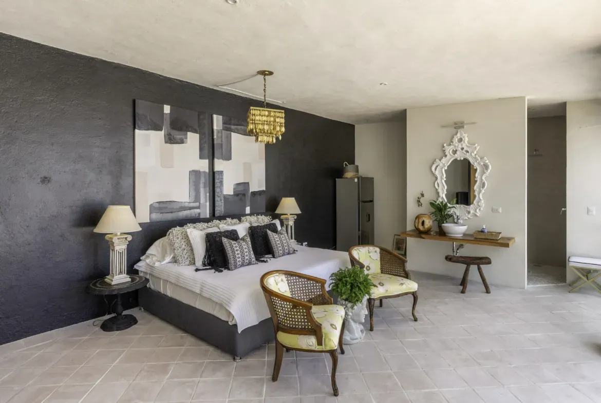 Casa Juan Guadiana, bedroom with a black accent wall and yellow armchairs, San Miguel de Allende