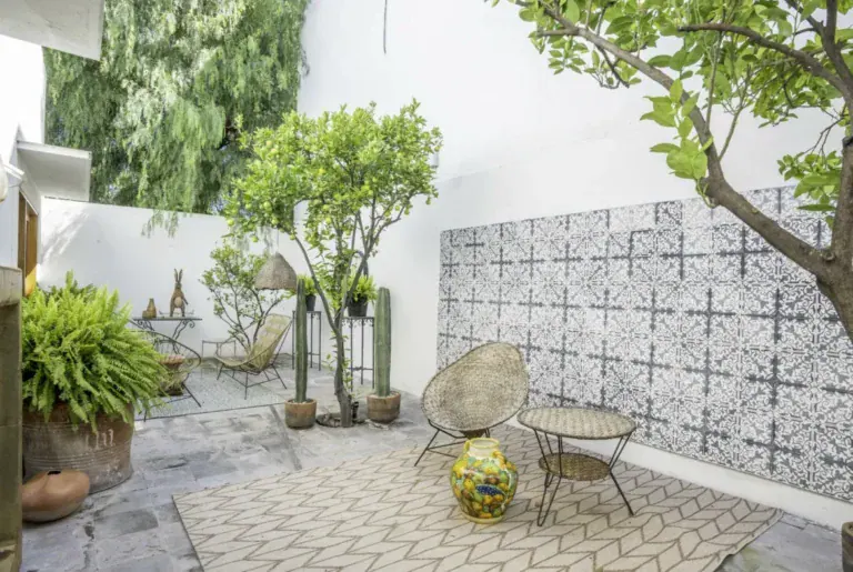 Casa Juan Guadiana, patio with a patterned tile wall, acapulco chairs and a lemon tree, San Miguel de Allende
