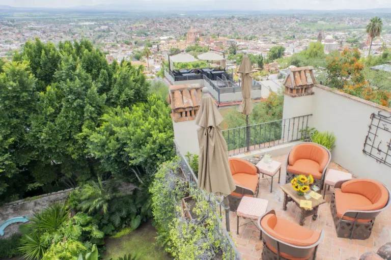 Casa Kate, terrace with orange chairs above a garden and a view of the town, San Miguel de Allende