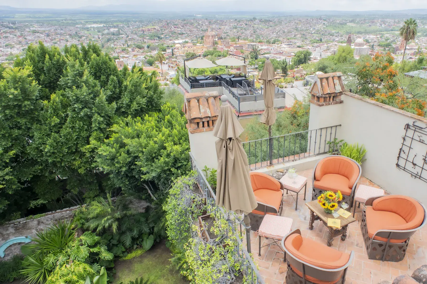 Casa Kate, terrace with orange chairs above a garden and a view of the town, San Miguel de Allende
