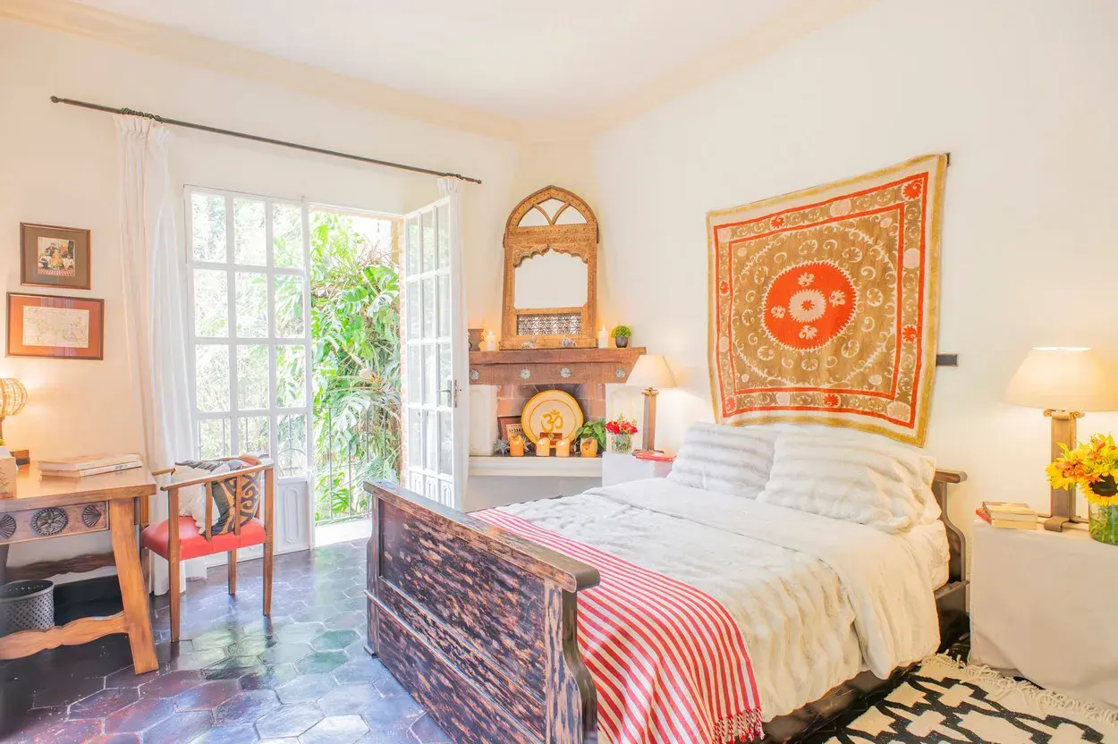 Casa Kate, bedroom with a red textile hanging and a wood bed frame, San Miguel de Allende