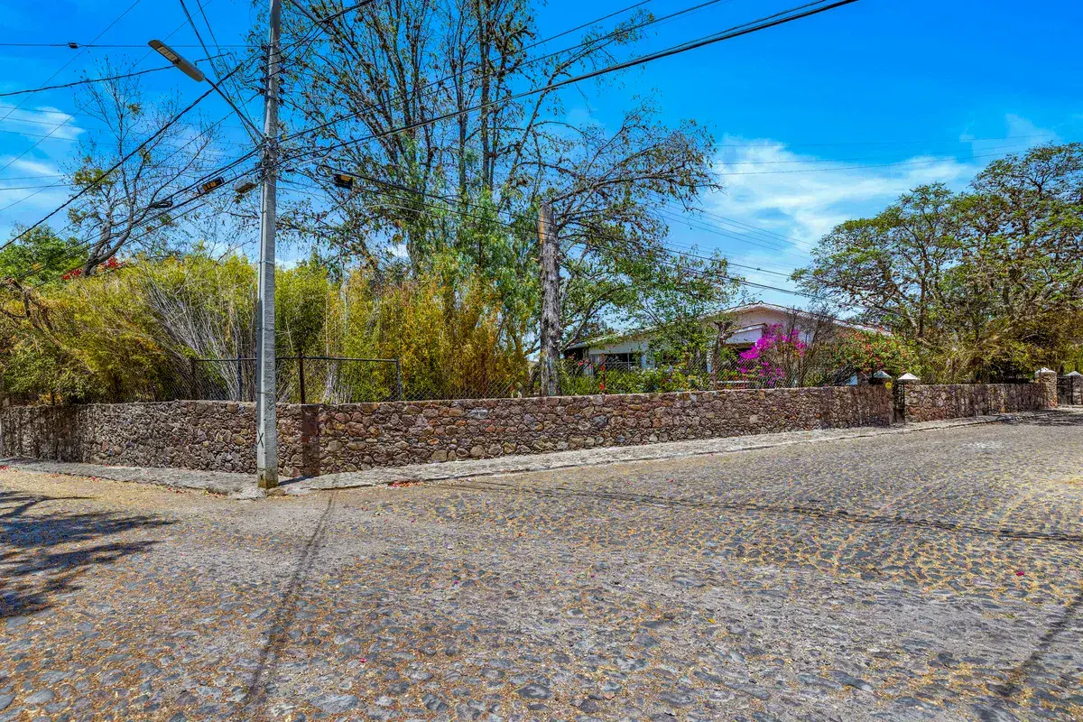 Casa La Chiquita, cobblestone street corner with a stone wall and trees outside the property, San Miguel de Allende