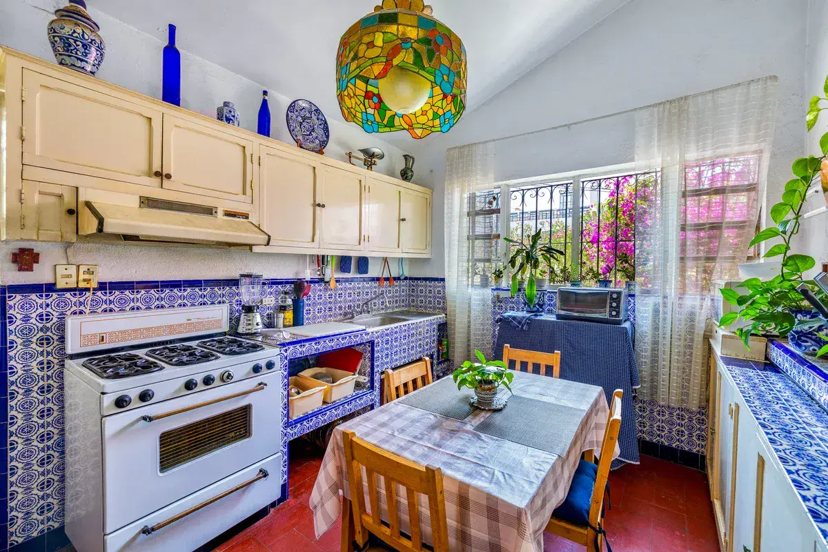Casa La Chiquita, kitchen with cream cabinets, blue and white tile, a white gas range and a stained-glass pendant lamp, San Miguel de Allende