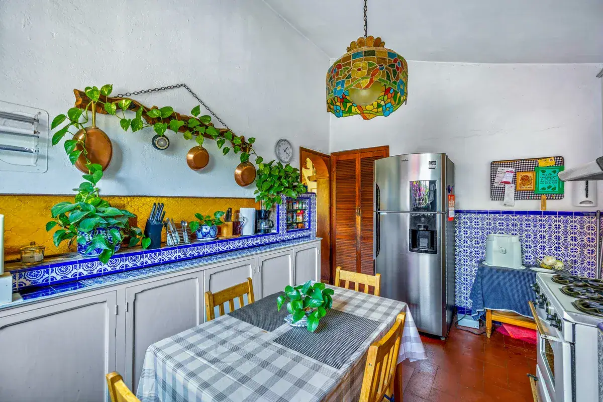 Casa La Chiquita, kitchen with blue and white tile counters, a stainless refrigerator, hanging copper pans and a breakfast table, San Miguel de Allende