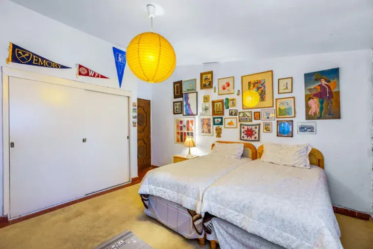 Casa La Chiquita, bedroom with twin beds, a wall of framed pictures and a built-in closet, San Miguel de Allende