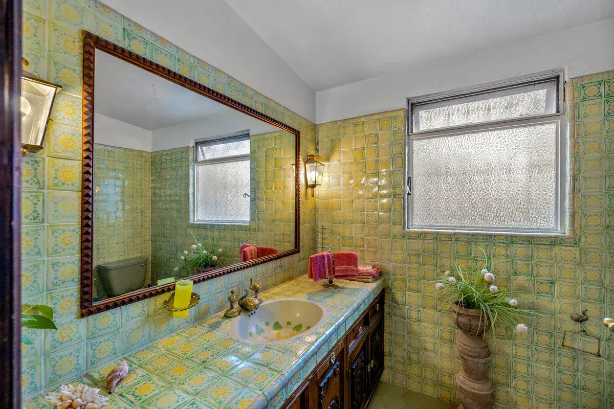Casa La Chiquita, bathroom with green and yellow tile, a long tile counter and a large framed mirror, San Miguel de Allende