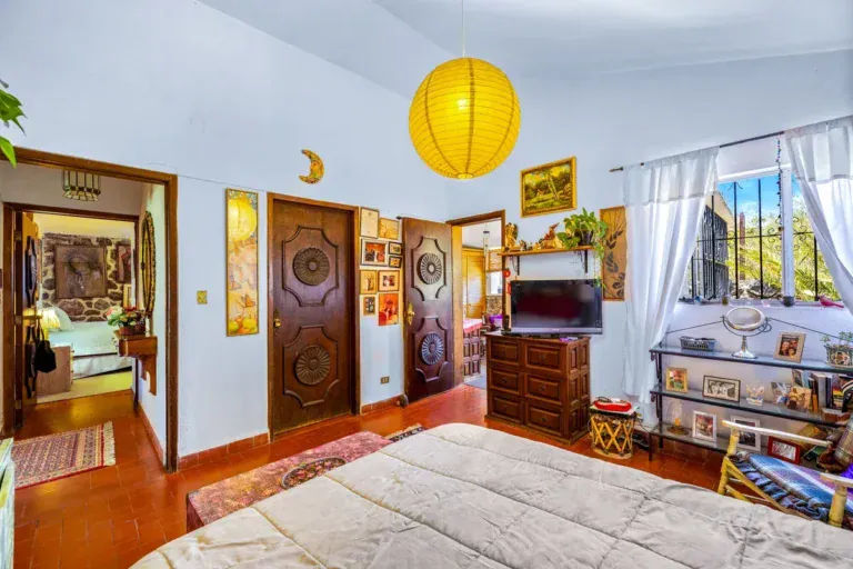 Casa La Chiquita, bedroom with a carved wood door, a double bed and a yellow paper lantern, San Miguel de Allende