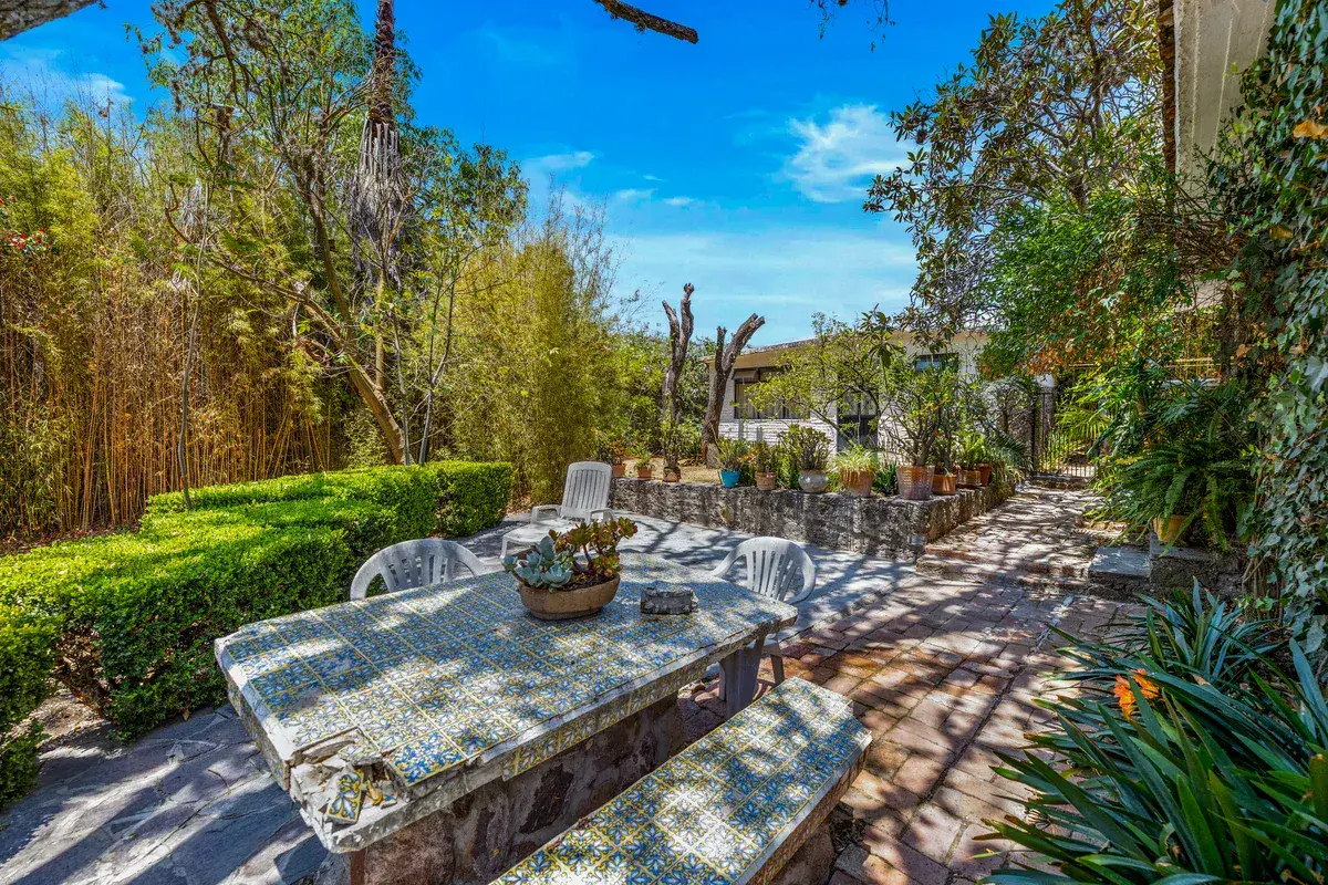 Casa La Chiquita, garden patio with a mosaic stone table with benches among bamboo and plants, San Miguel de Allende
