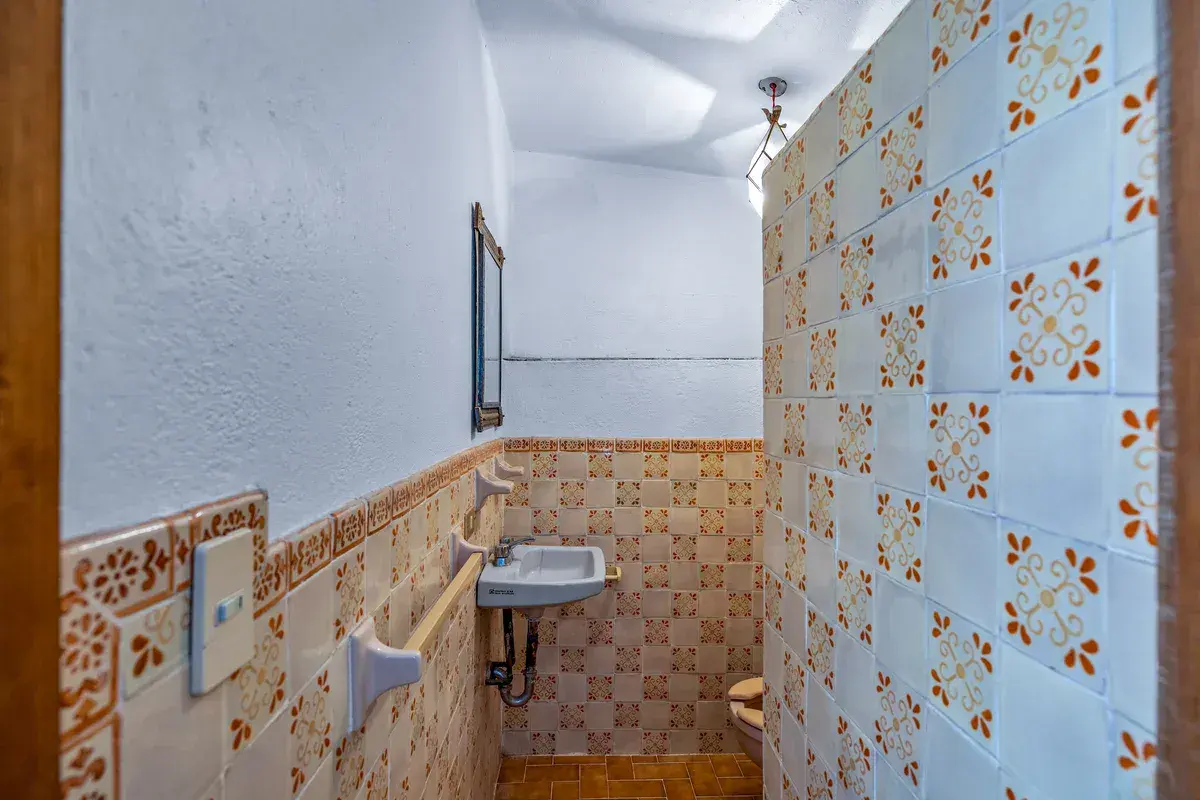 Casa La Chiquita, bathroom with orange and white patterned tile, a small sink and a wooden door, San Miguel de Allende