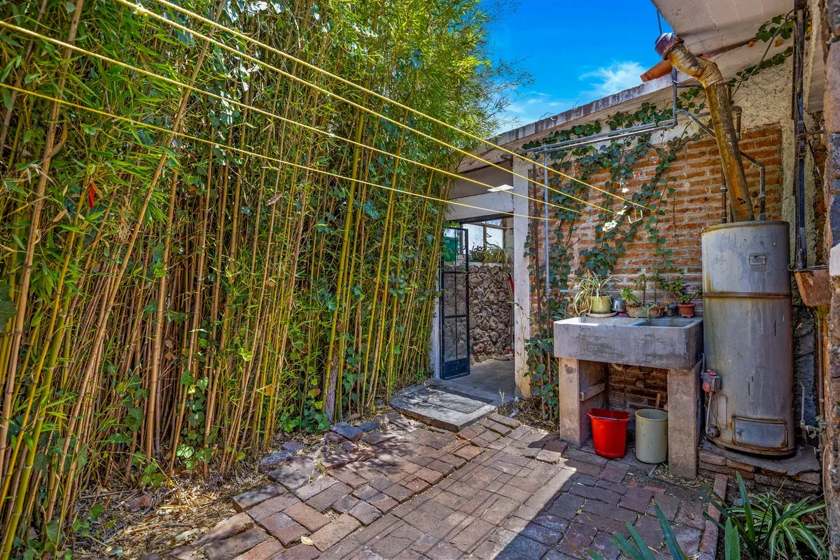 Casa La Chiquita, service yard with bamboo, a stone sink, a water heater and a brick wall, San Miguel de Allende