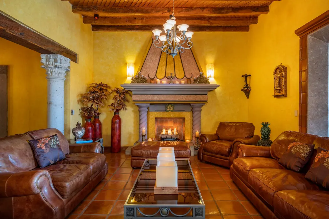 Casa La Colina, living room with a stone fireplace, leather sofas and a beamed ceiling, San Miguel de Allende