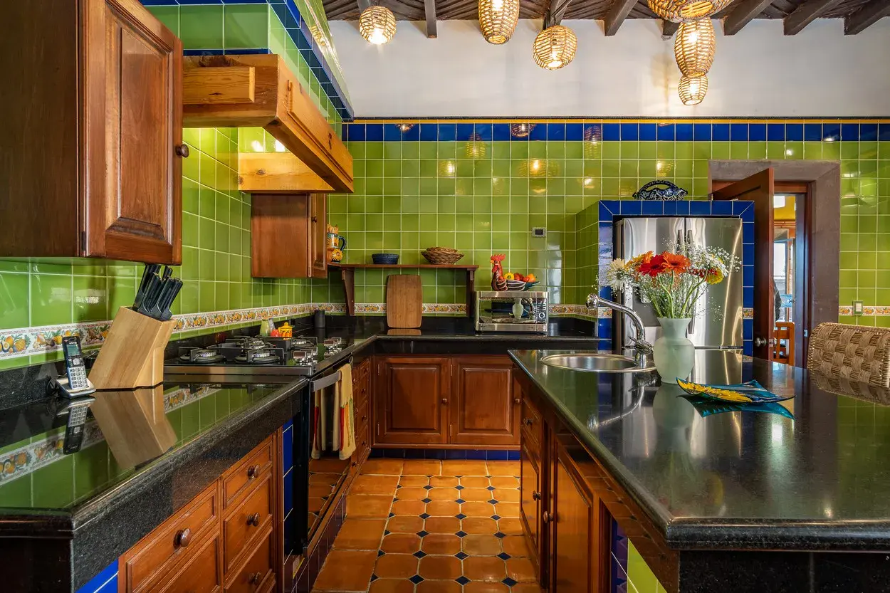 Casa La Colina, kitchen with green tile, a black granite island and blue accents, San Miguel de Allende
