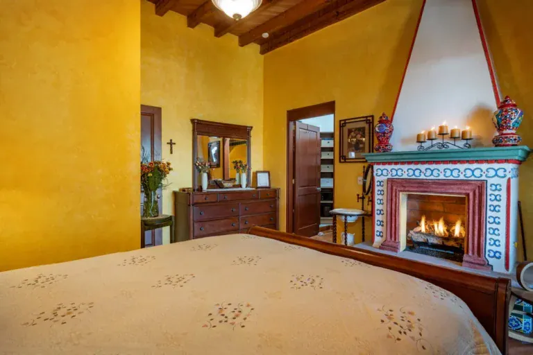 Casa La Colina, bedroom with a tiled fireplace and an embroidered bedspread, San Miguel de Allende