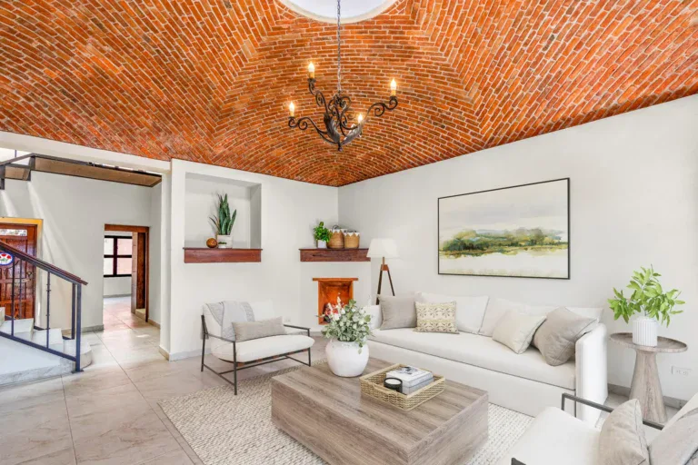 Casa Las Monjas, living room with a brick vaulted ceiling, a skylight, a white sofa and a corner fireplace (virtually staged), San Miguel de Allende