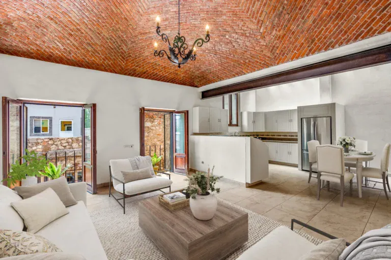 Casa Las Monjas, living room and open kitchen with a dining table beyond, under a brick vaulted ceiling (virtually staged), San Miguel de Allende