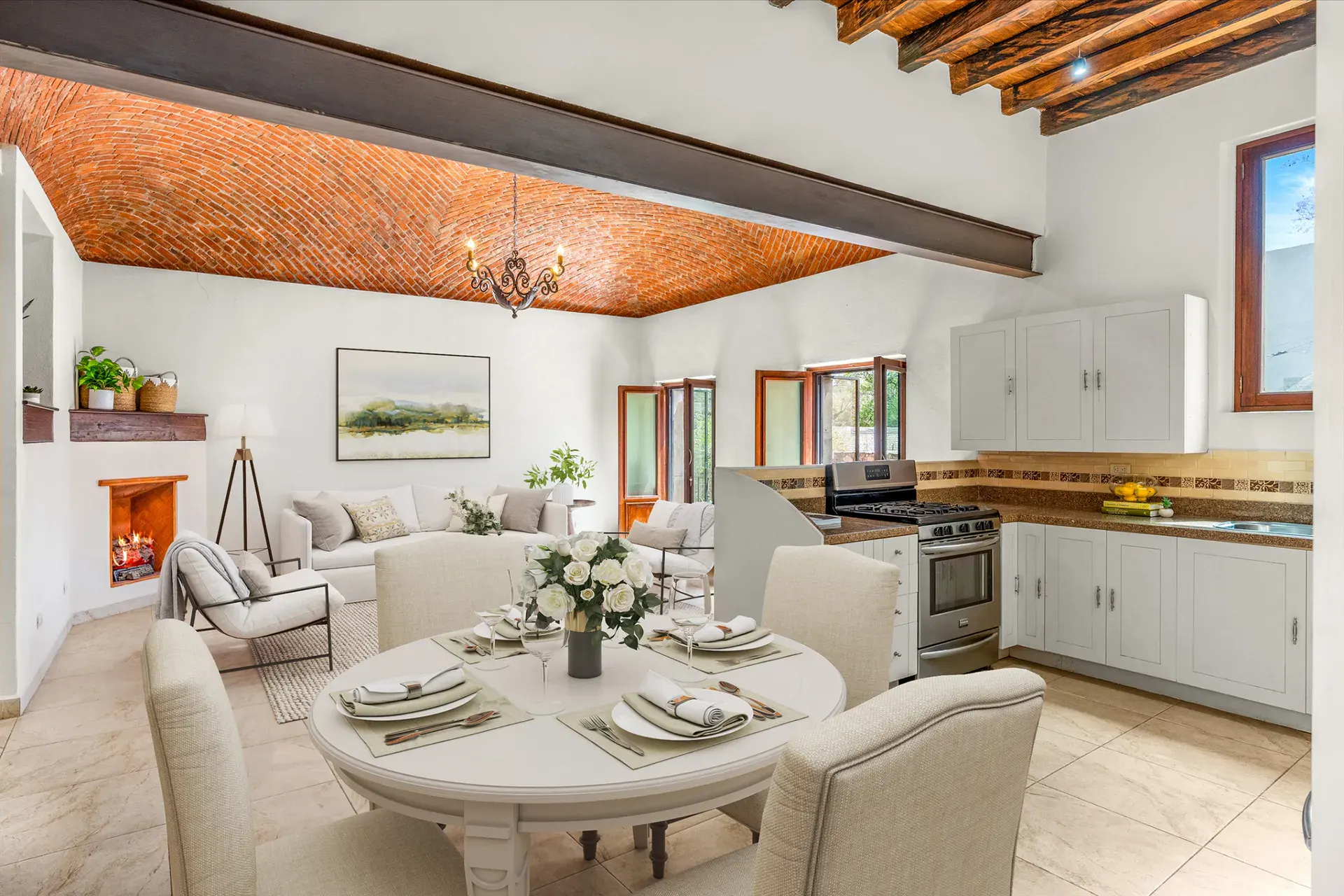 Casa Las Monjas, living, dining and kitchen area with a round dining table set for dinner, a sofa and white cabinets (virtually staged), San Miguel de Allende