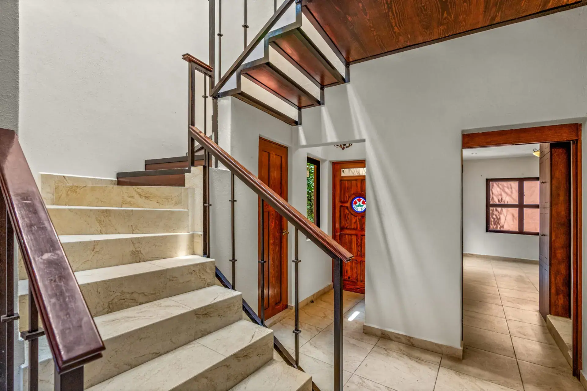 Casa Las Monjas, stairwell with pale stone steps, a dark wood handrail and open steel and wood stairs above, San Miguel de Allende