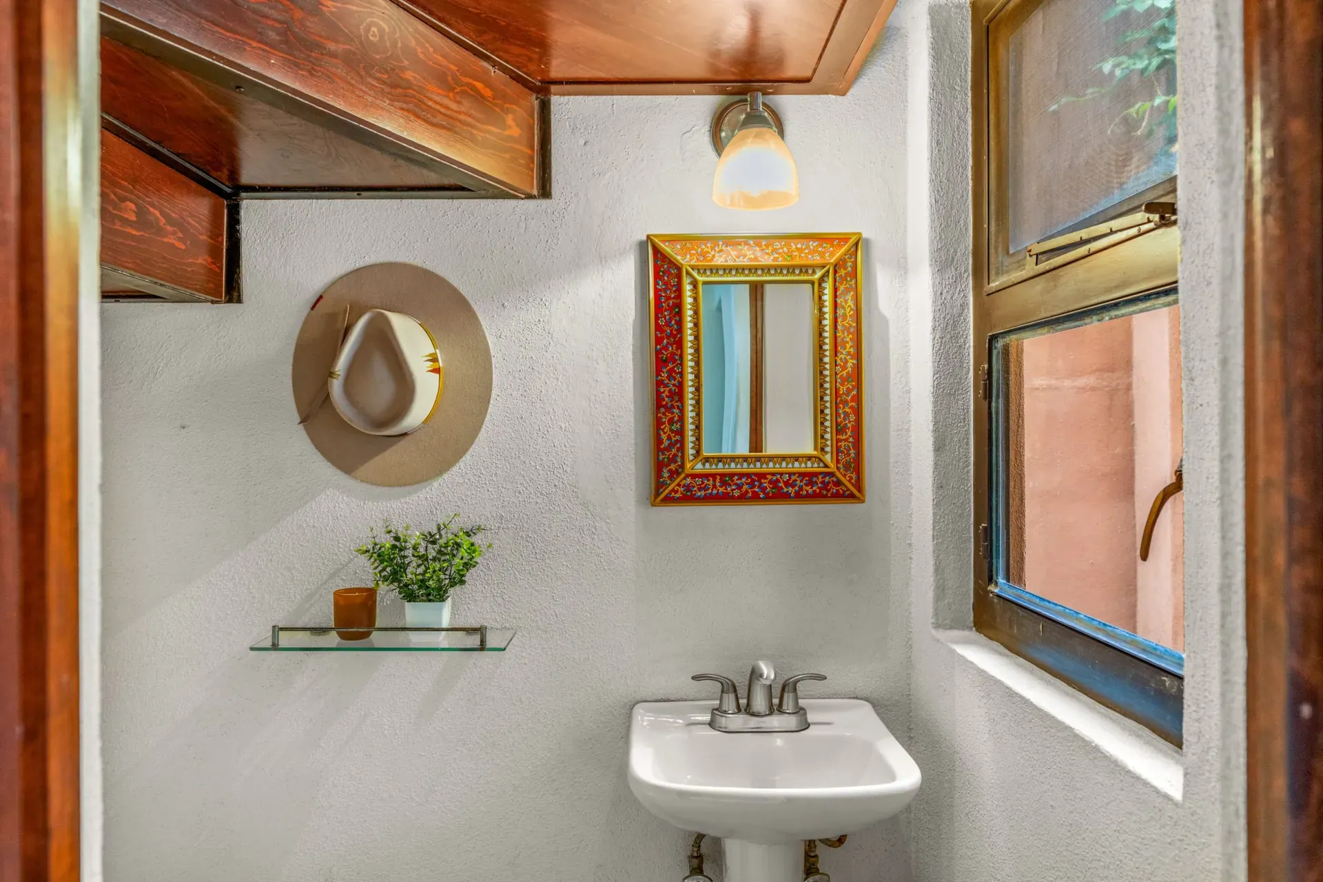 Casa Las Monjas, powder room with a pedestal sink, a Mexican framed mirror, a straw hat and a window, San Miguel de Allende