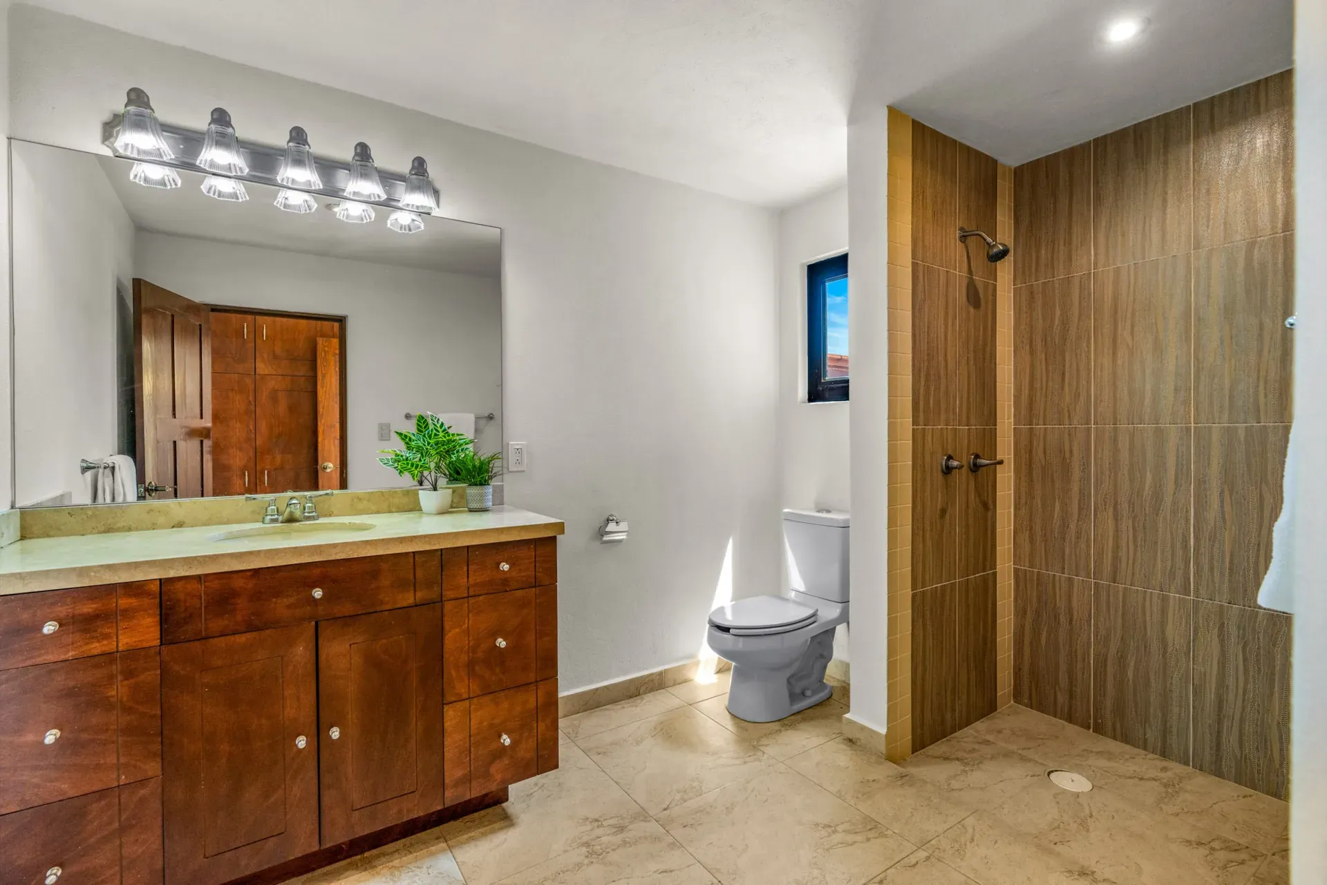 Casa Las Monjas, bathroom with a wood vanity, a mirror with vanity lights and a shower with wood-look tile, San Miguel de Allende