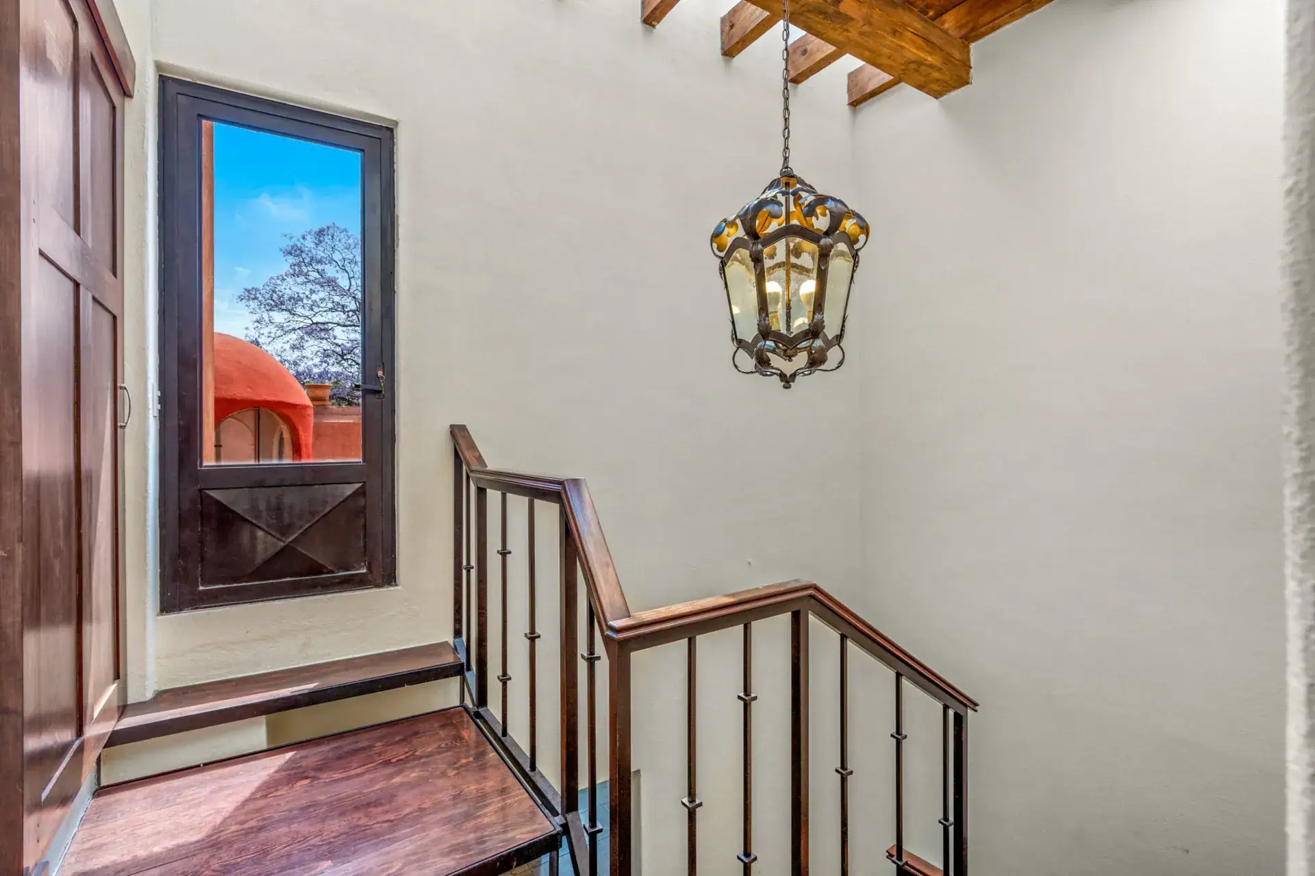 Casa Las Monjas, stair landing with a wood and glass window, a hanging lantern and a steel railing, San Miguel de Allende