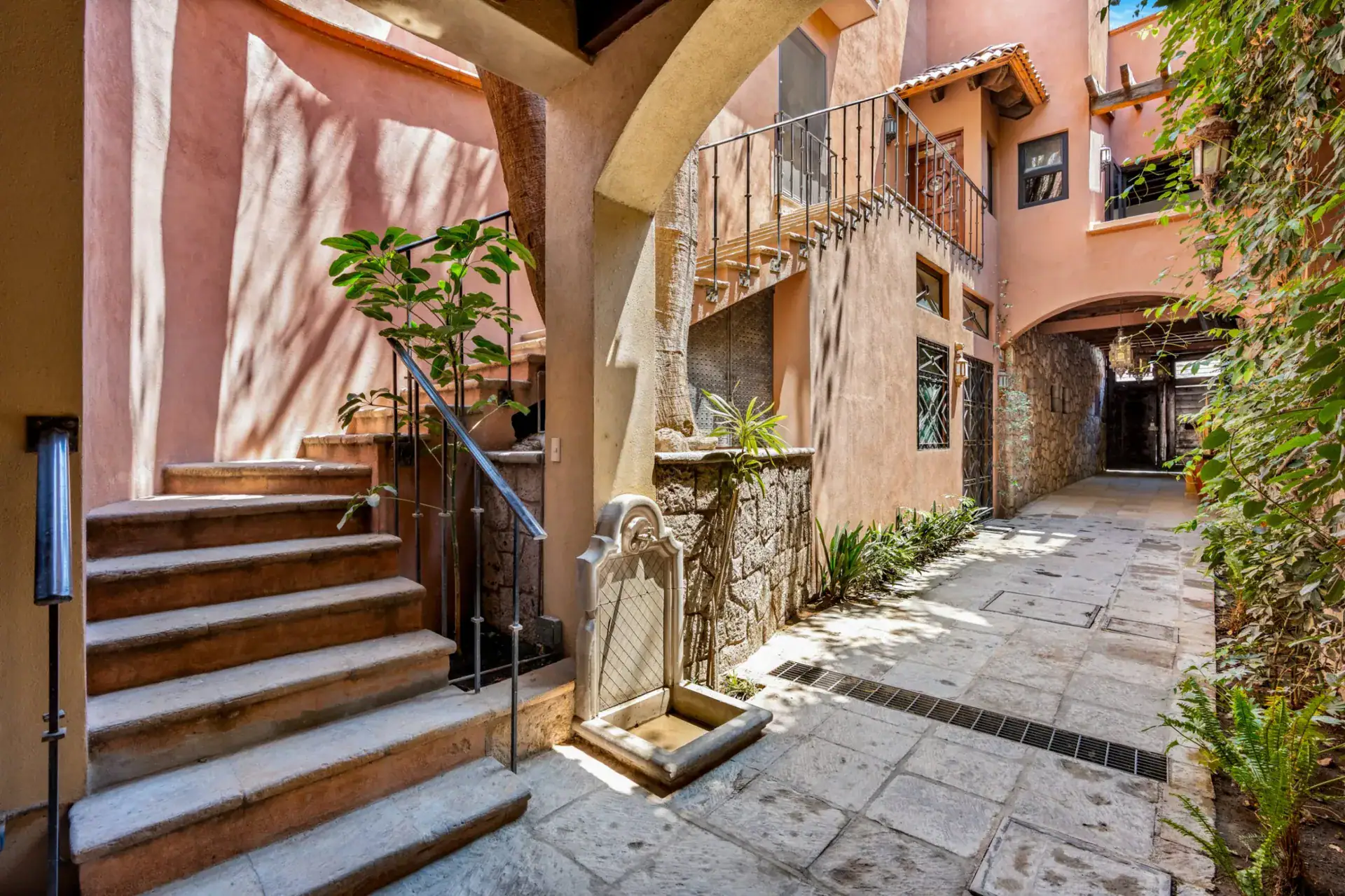 Casa Las Monjas, stone paved passage between buildings with a stair, a plant and an arch, San Miguel de Allende