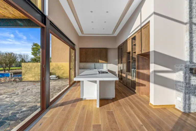 Casa Lavanda, kitchen with a white quartz island seen through a sliding glass door to a stone patio and pool, San Miguel de Allende