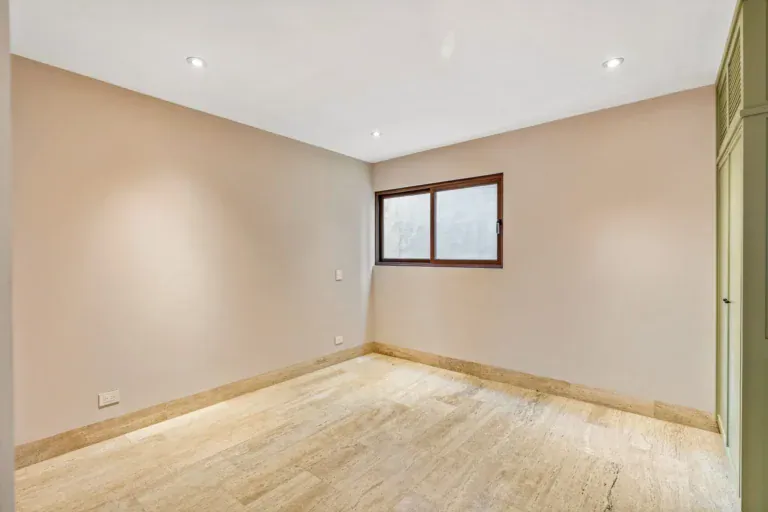 Casa Lavanda, empty bedroom with a pale pink wall, a window and travertine-look flooring, San Miguel de Allende