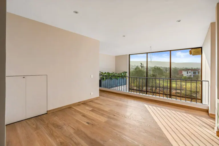 Casa Lavanda, empty room with a wide glass wall opening to a balcony facing a green landscape, San Miguel de Allende