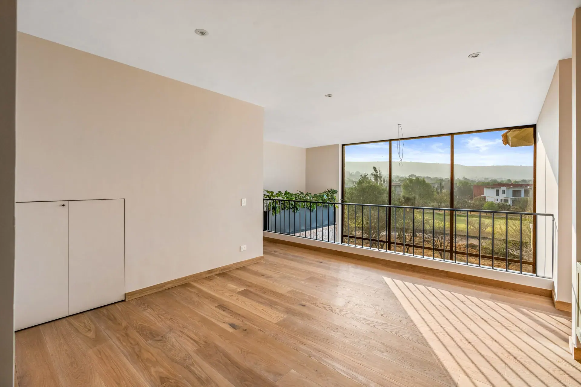 Casa Lavanda, empty room with a wide glass wall opening to a balcony facing a green landscape, San Miguel de Allende