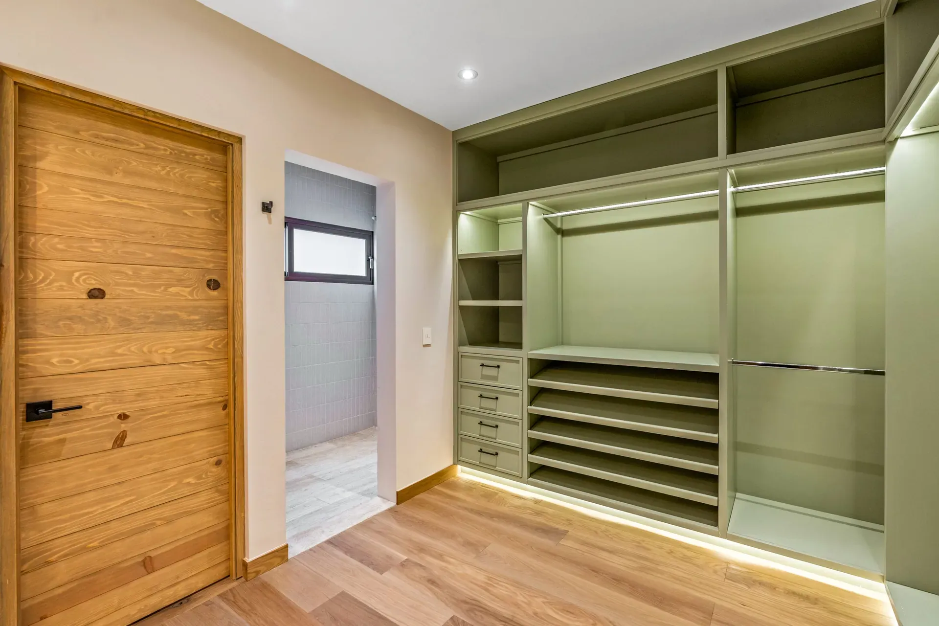 Casa Lavanda, closet with sage green shelving and hanging rails behind a wood door, San Miguel de Allende