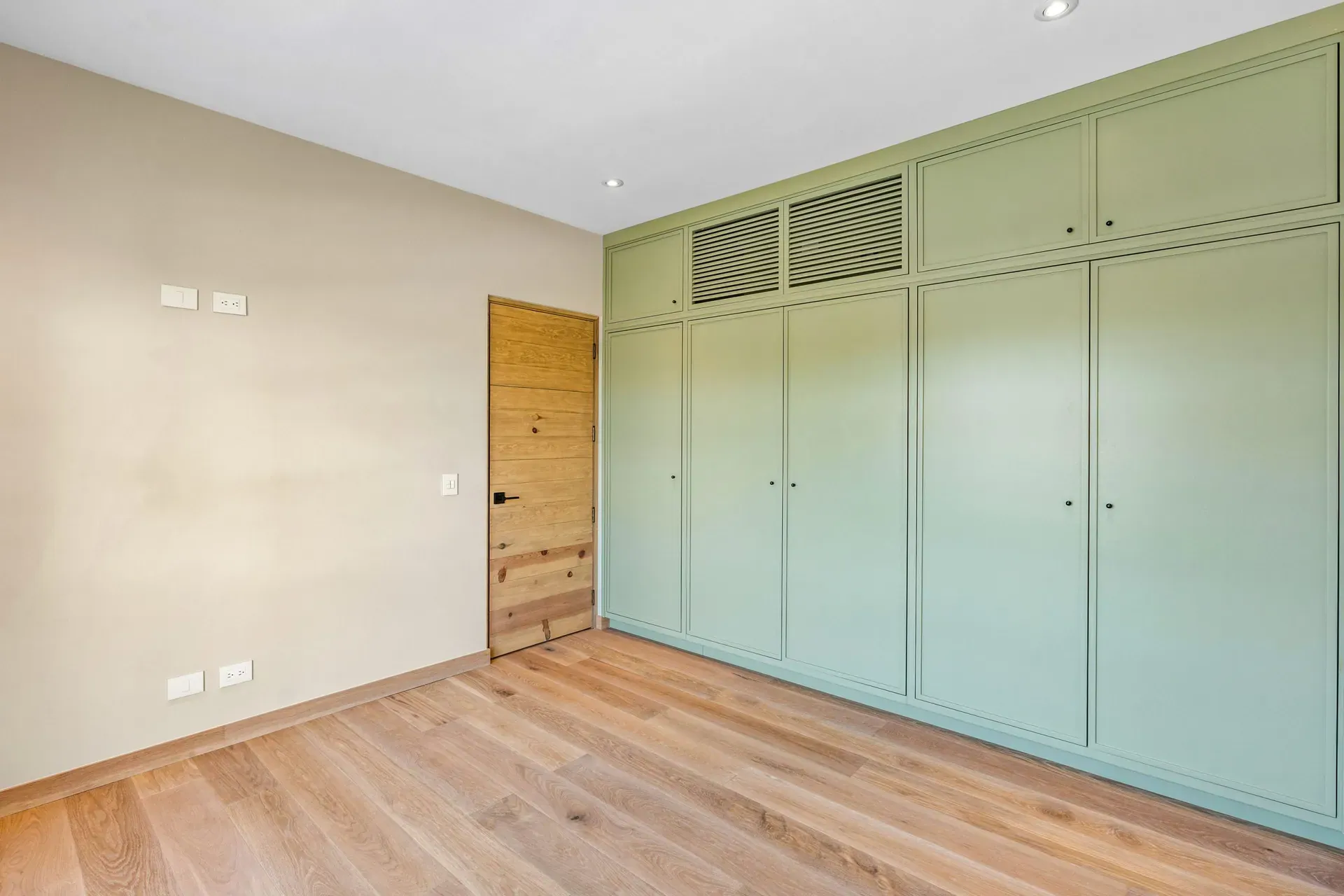 Casa Lavanda, bedroom with a mint green built-in wardrobe, a wood door and oak floors, San Miguel de Allende
