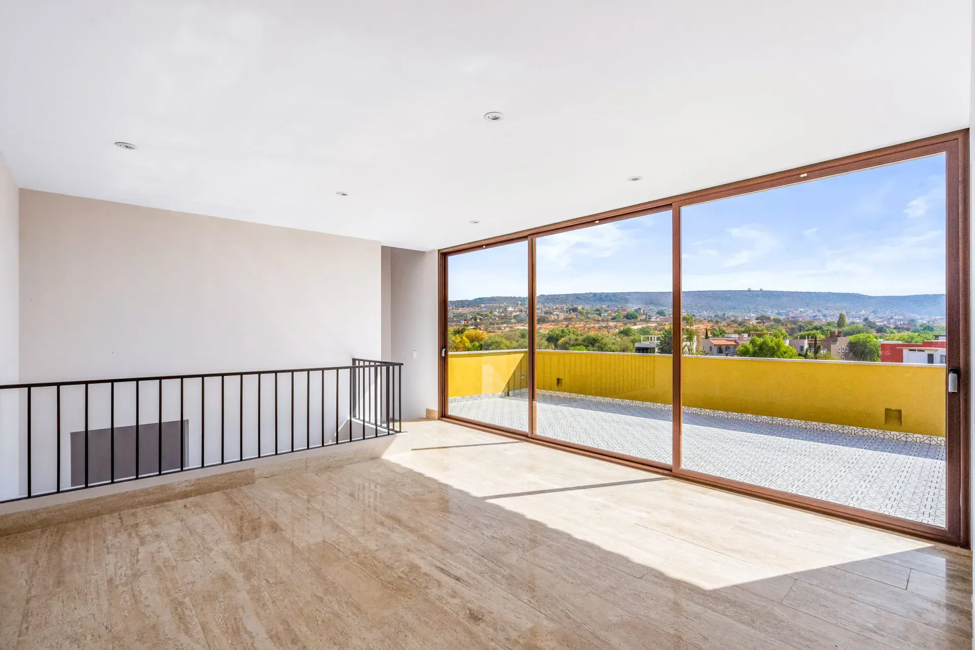 Casa Lavanda, empty upper room with an iron railing and a sliding glass wall to a terrace overlooking the golf course, San Miguel de Allende
