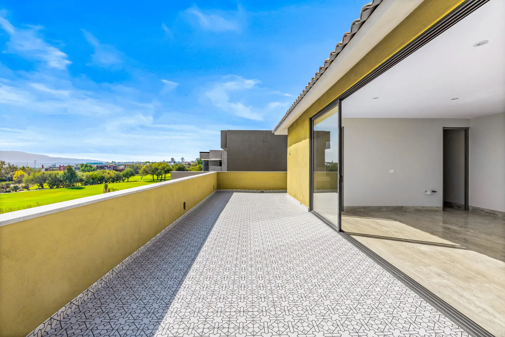 Casa Lavanda, tiled terrace with a yellow wall facing the golf course, hills and sky, San Miguel de Allende