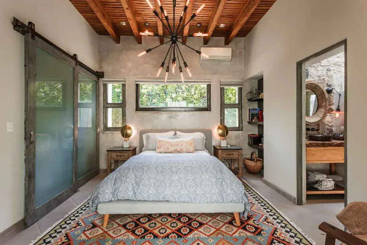 Casa Lily, bedroom with a patterned rug, a barn-style door and a sunburst chandelier, San Miguel de Allende