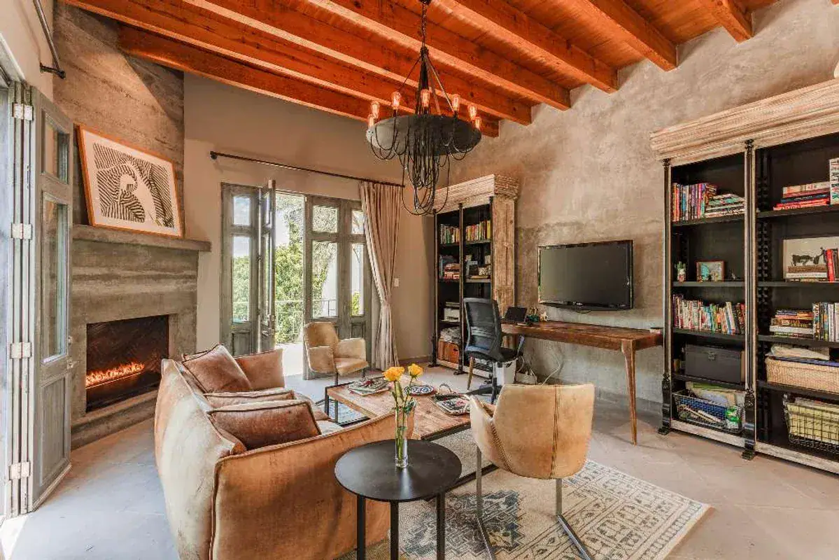 Casa Lily, study with a gas fireplace, black bookshelves and a wood beam ceiling, San Miguel de Allende