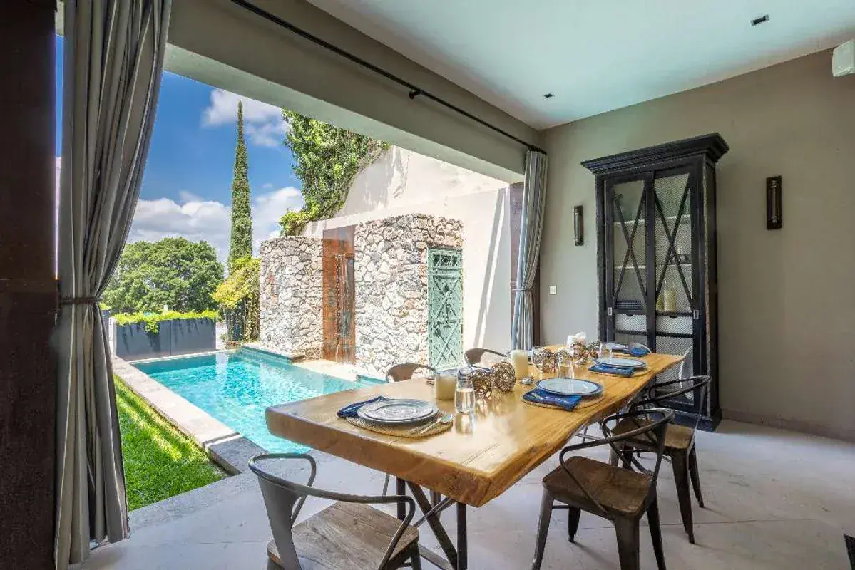 Casa Lily, terrace dining table beside the pool with a stone tower in the garden, San Miguel de Allende