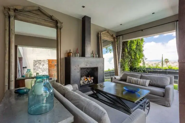 Casa Lily, outdoor living room with a fireplace and gray sofas facing the view, San Miguel de Allende
