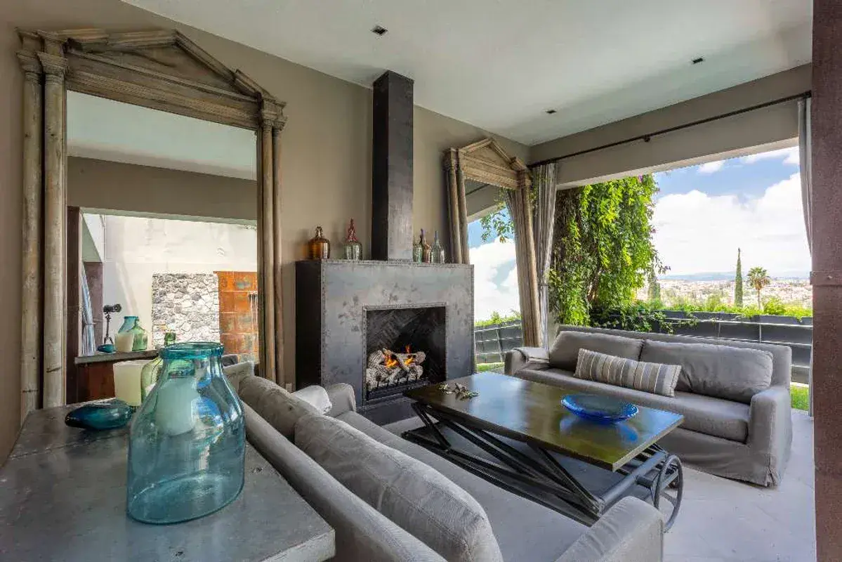 Casa Lily, outdoor living room with a fireplace and gray sofas facing the view, San Miguel de Allende