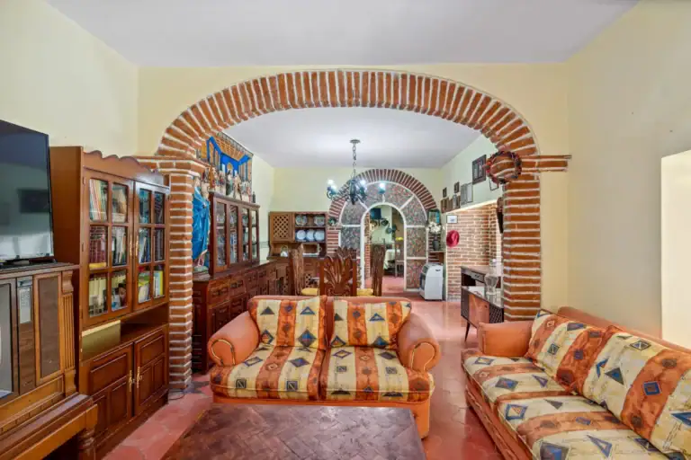 Casa Los Helechos, living room with striped sofas and a brick arch leading to the dining room, San Miguel de Allende