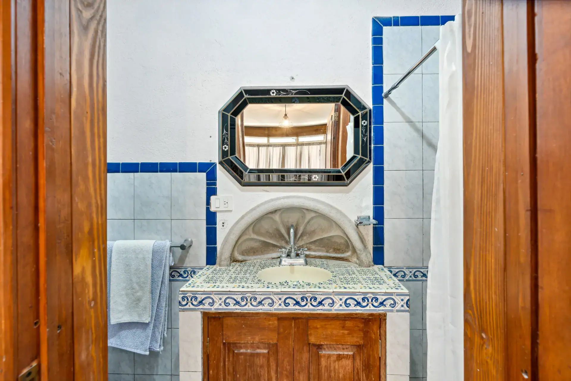Casa Los Helechos, bathroom with a tiled vanity, an octagonal mirror and blue tile trim, San Miguel de Allende