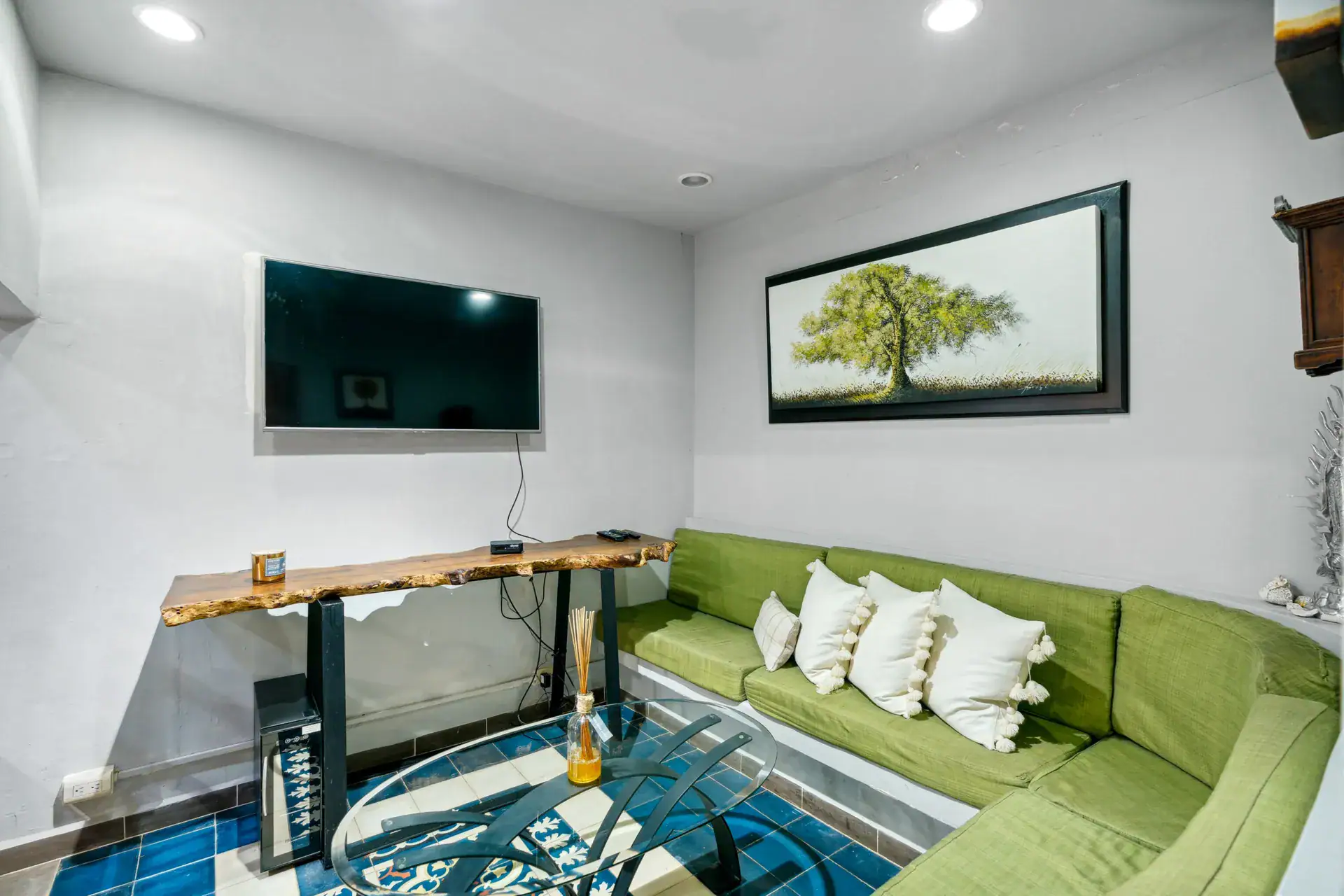 Casa Los Helechos, lounge with a green sectional, a television and a glass coffee table, San Miguel de Allende
