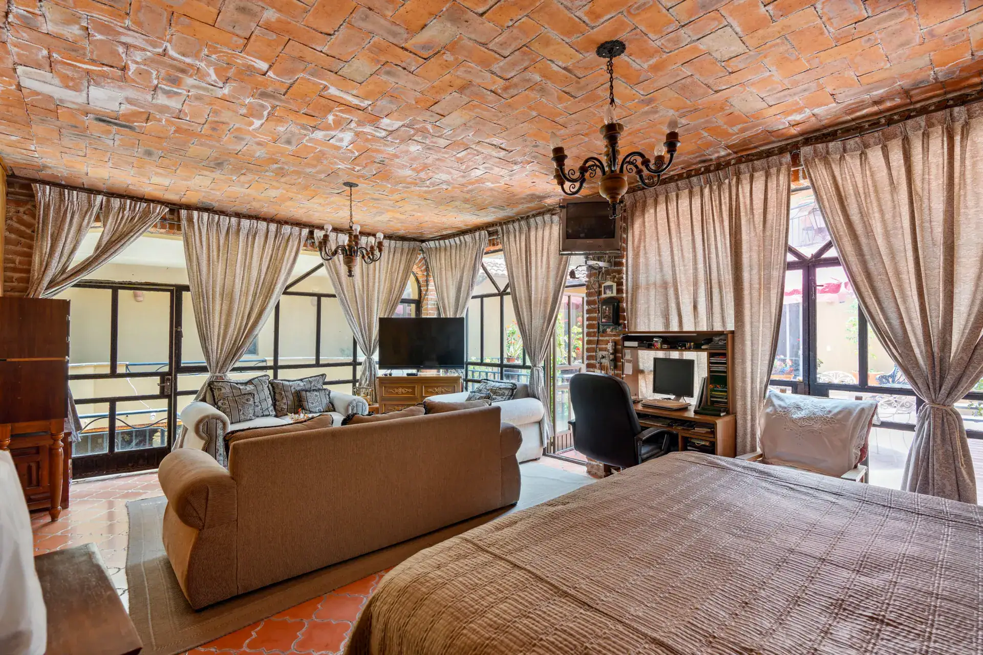 Casa Los Helechos, living and sleeping suite with a brick vaulted ceiling, a sofa, a desk and curtained windows, San Miguel de Allende