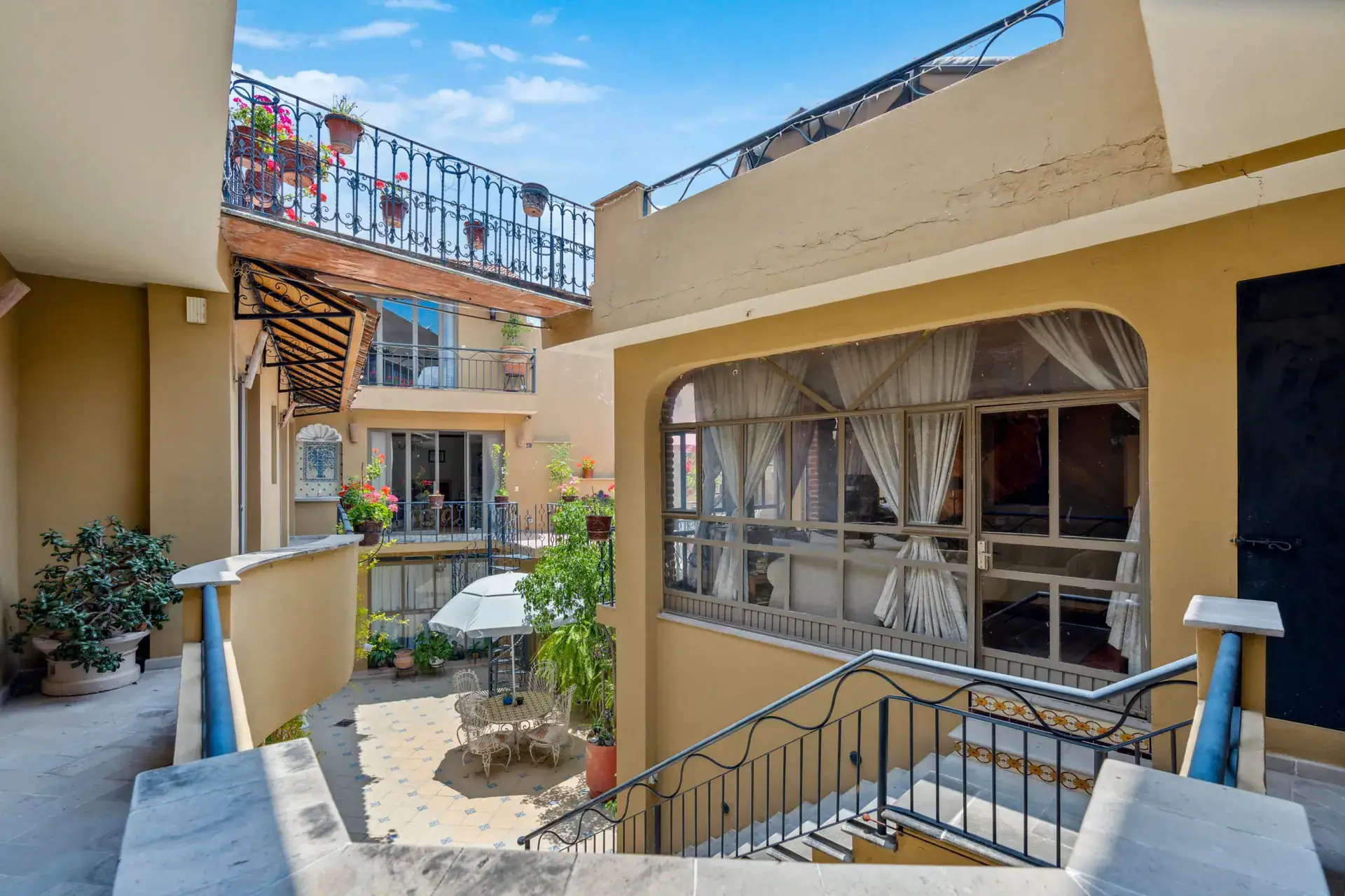 Casa Los Helechos, upper terrace with a curtained room, an iron staircase and a view of the neighboring roofs, San Miguel de Allende